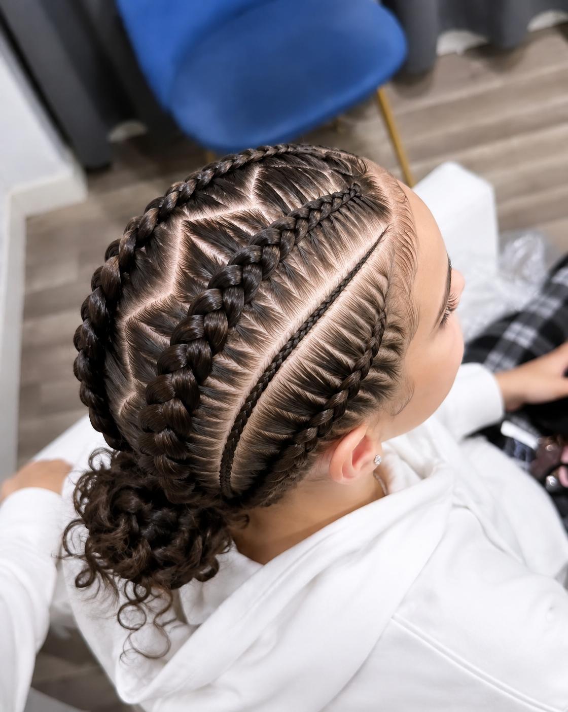 Tresses plaquées géométriques réunies en chignon bas bouclé